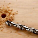 Drill bit with newly drilled hole and wood shavings