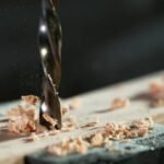 Detail of drill making hole into plywood, closeup.