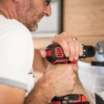 Handyman drilling a hole in the wooden wall