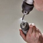 Drilling mirror with glass drill bit clamped in chuck.